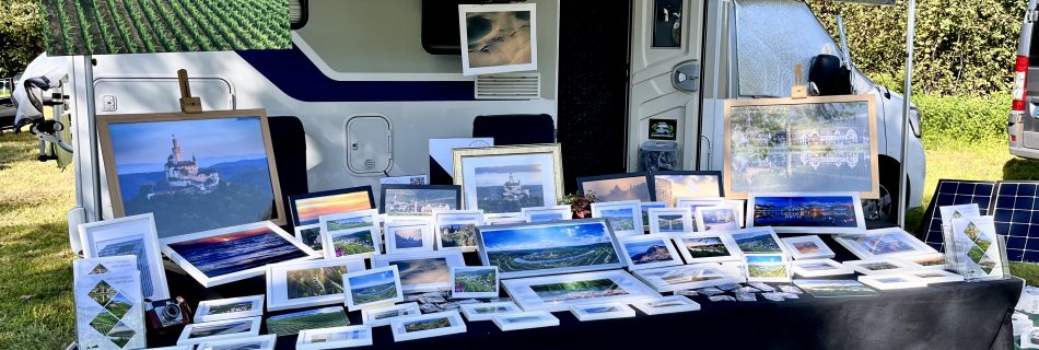 Stall with lots of photos on display introns of a camper van.